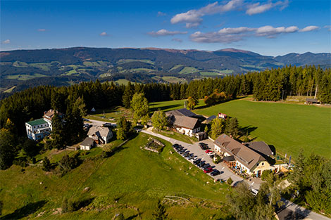 Blick aus der Vogelperspektive - der Gasthof Orthofer mitten in der Natur - umgeben von Wäldern und Bergen.
