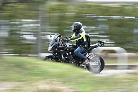 Motorradfahrer auf der Straße - mit Helm und Motorradjacke ausgestattet.