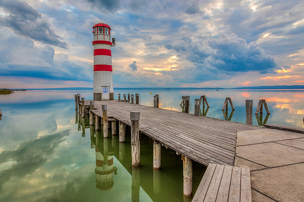 Blick auf den Neusiedlersee - im Vordergrund ein Steg ins Wasser und ein Leuchtturm